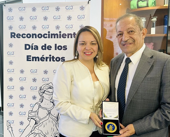 La decana entrega un reconocimiento a un profesor durante un acto academico ambos sonrien frente a un cartel institucional