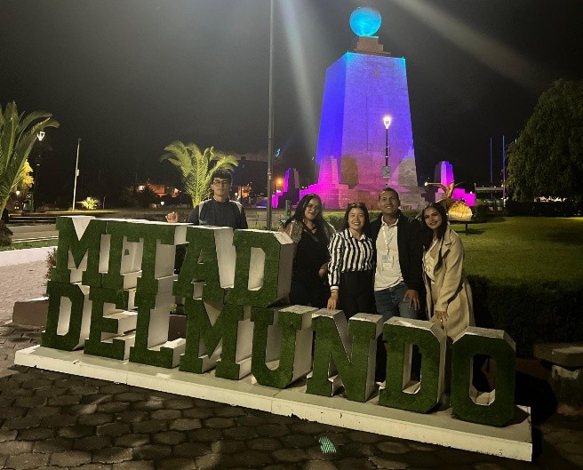 un grupo de representantes de la Universidad Antonio Nariño posa sonriente frente al letrero “Mitad del Mundo” en Quito, Ecuador