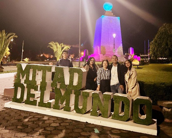 un grupo de representantes de la Universidad Antonio Nariño posa sonriente frente al letrero “Mitad del Mundo” en Quito, Ecuador