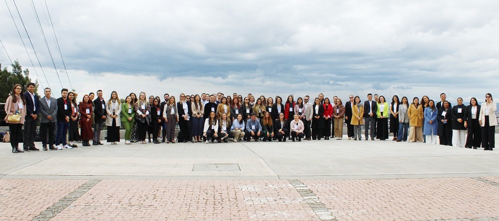 Un grupo muy numeroso de personas posa al aire libre para una foto grupal con un cielo nublado de fondo